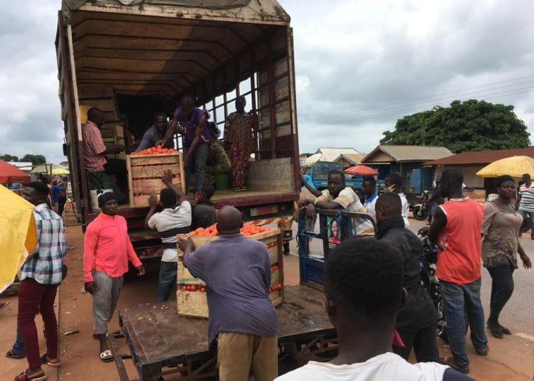 Ghanaian tomato traders and cargo trucks at border crossing between Ghana and Burkina Faso