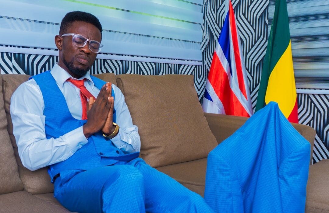 Ghanaian corporate worker planning a side business Ghana 2026 on a laptop with a notebook and mobile phone