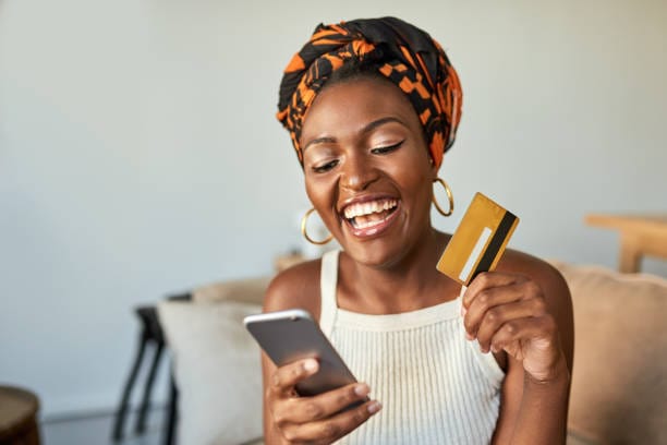 Ghanaian woman using mobile phone contactless payment card in Accra market digital finance
